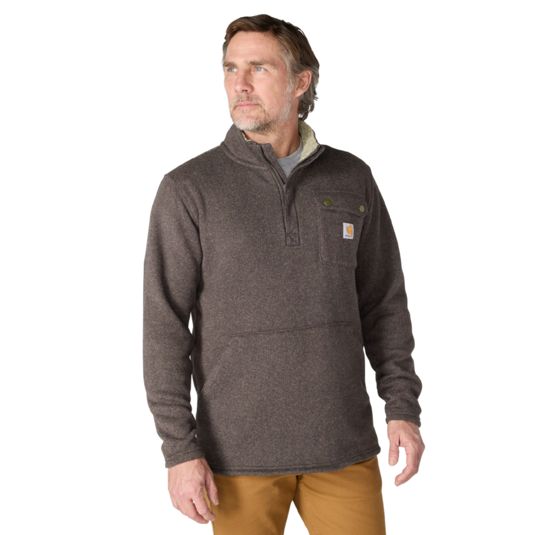 A man wearing a dark brown heathered quarter-zip fleece pullover with a chest pocket and a visible Carhartt logo patch, paired with tan pants, against a plain white background.