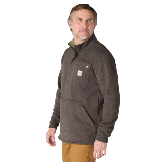 A man wearing a dark brown Carhartt quarter-zip fleece pullover jacket with a small orange and white Carhartt logo patch on the chest pocket, paired with tan pants, photographed against a solid white background.