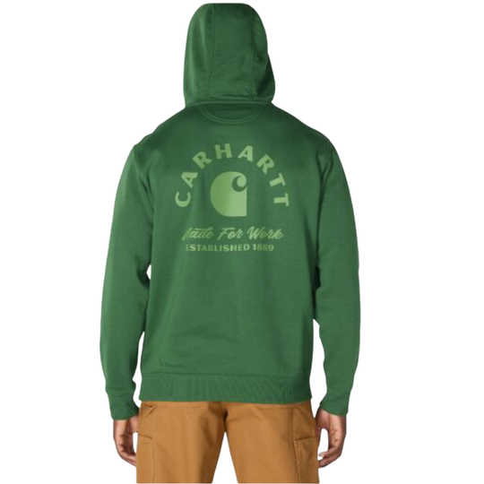 A person shown from the back wearing a green hooded sweatshirt with a large light green Carhartt logo and text printed across the back, paired with tan pants, on a plain white background.