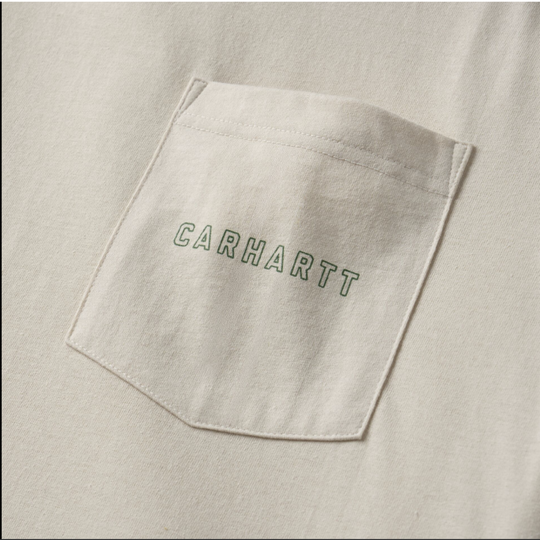 Close-up of a light beige or off-white fabric pocket with green outlined 'CARHARTT' lettering on the front, showing the texture of the material.