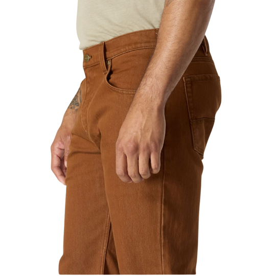A close-up side view of a person wearing brown denim jeans, showing the side pocket, waistband, and hand against a plain white background.