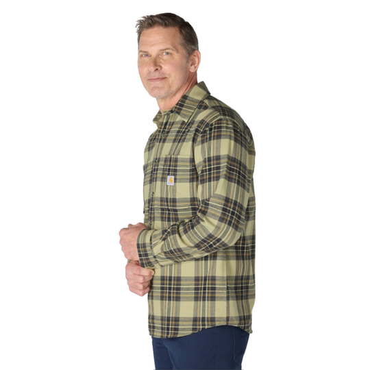 A man wearing a Carhartt long-sleeve plaid button-down shirt in olive green and tan, paired with navy pants, shown from a side profile against a white background.