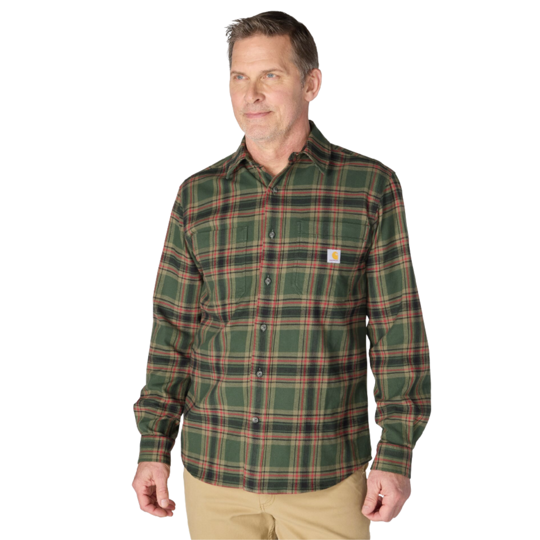 A man wearing a green Carhartt plaid button-down shirt with red and black stripes, paired with khaki pants, against a plain white background.