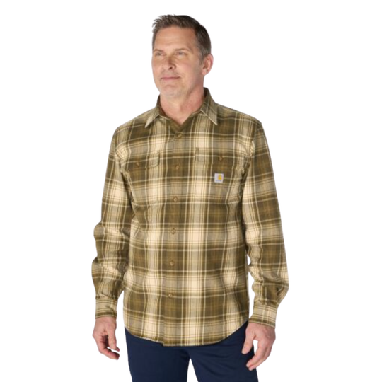 A man wearing a Carhartt long-sleeve plaid button-up shirt in olive green and beige, paired with dark blue pants, against a plain white background.