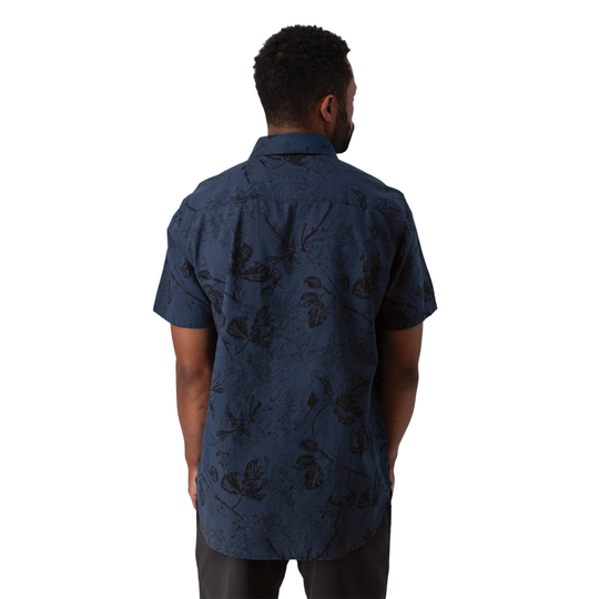 A man viewed from behind wearing a short-sleeve button-up shirt in dark navy blue with a subtle black tropical floral pattern, set against a plain white background.