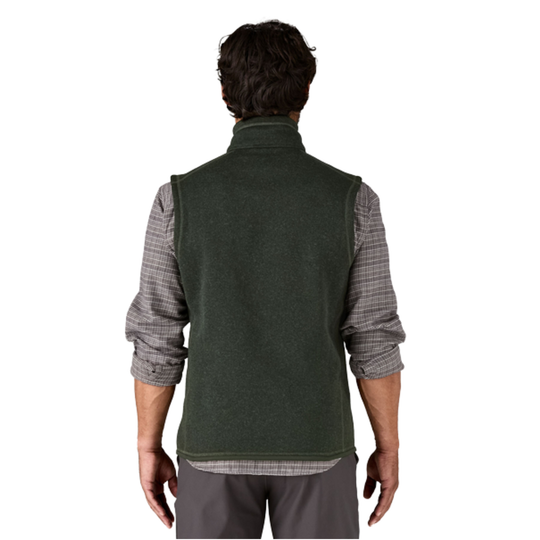 A man viewed from the back wearing a dark green fleece vest over a gray and white plaid long-sleeve shirt, set against a plain white background.