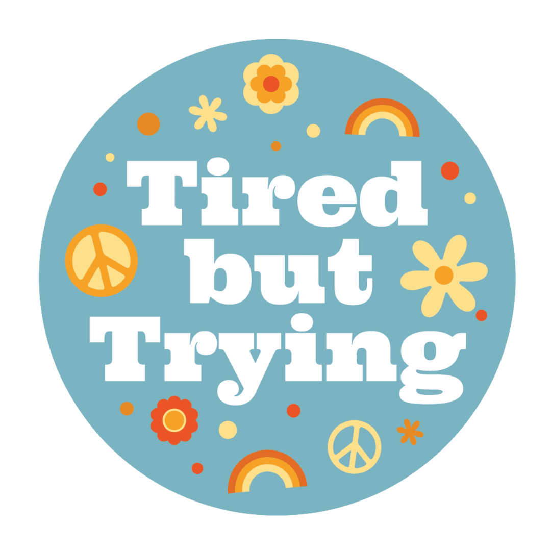 A circular graphic with the phrase 'Tired but Trying' in large white retro-style lettering on a light blue background, decorated with small yellow flowers, orange and yellow peace signs, rainbows, and dots.