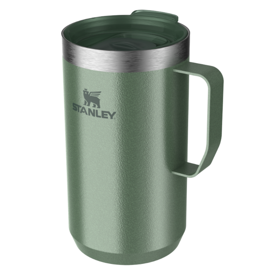 A green Stanley travel mug with a matching lid and handle, featuring the Stanley logo on the front, set against a plain white background.
