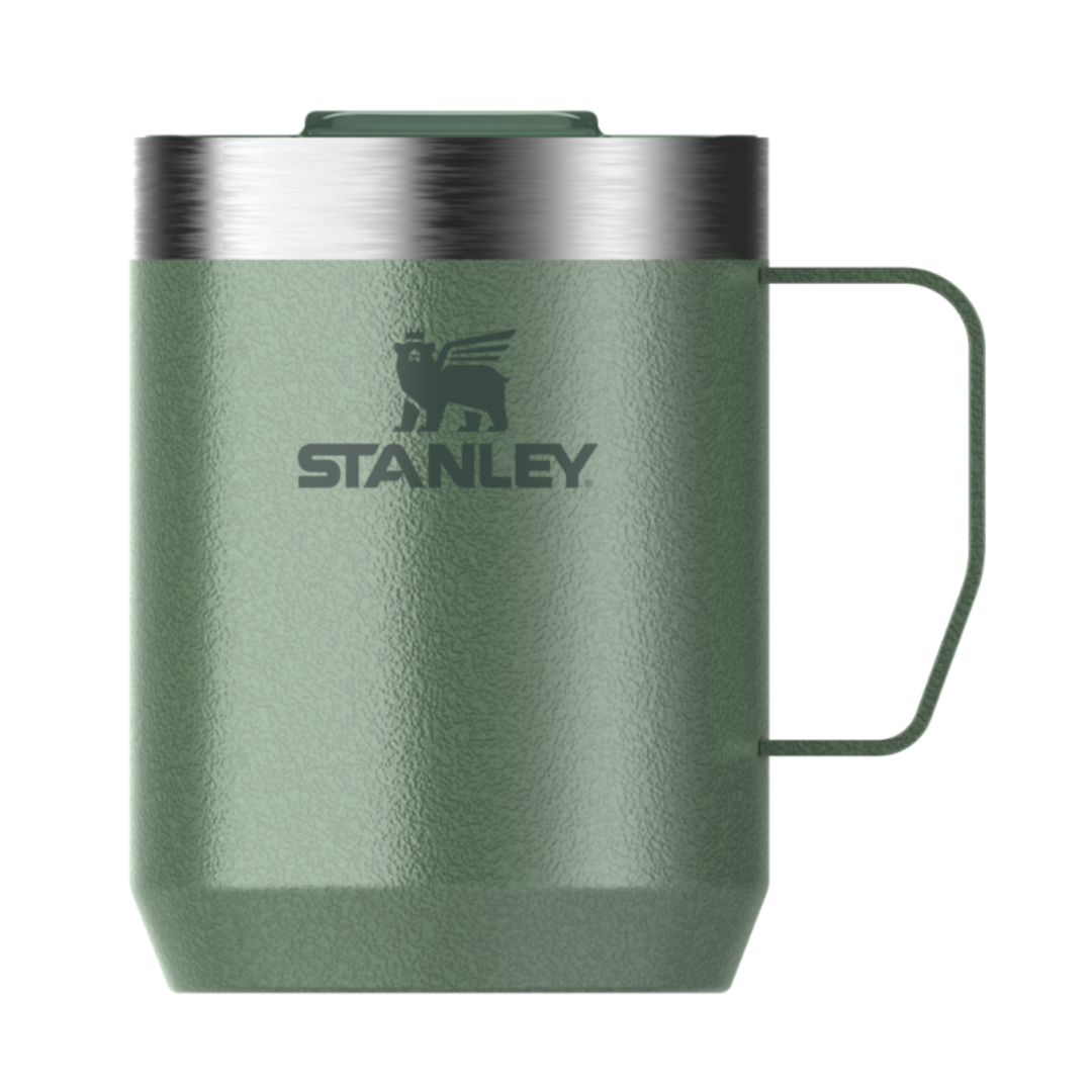An olive green Stanley travel mug with a stainless steel rim, a dark green handle, and the Stanley logo printed on the front, set against a plain white background.