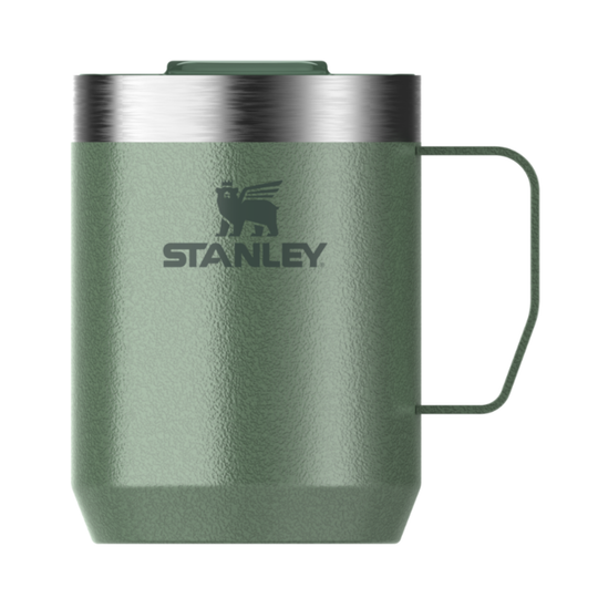 An olive green Stanley travel mug with a stainless steel rim, a dark green handle, and the Stanley logo printed on the front, set against a plain white background.