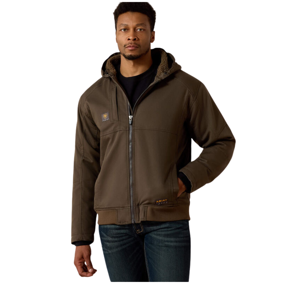 A man wearing a brown hooded work jacket with a zip-up front, fleece-lined hood, and side pockets, paired with dark blue jeans against a plain white background.