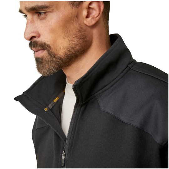 Close-up side profile of a man wearing a black technical zip jacket with a high collar over a white shirt, on a white background.