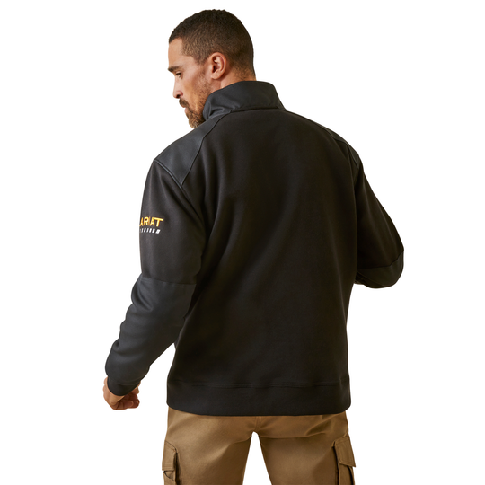 A man wearing a black quarter-zip pullover jacket with a yellow and white Carhartt logo on the left sleeve, shown from a rear three-quarter view against a white background.