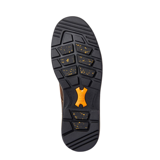 A top-down view of a shoe's black rubber sole, featuring a textured tread pattern with small yellow-green speckles and a bright orange central logo accent.