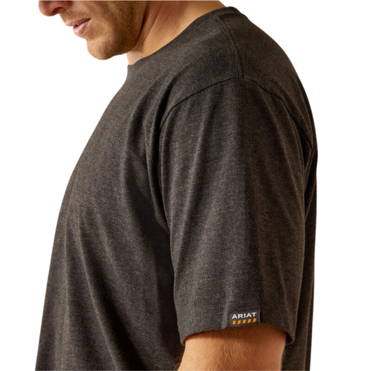 A close-up side profile of a man wearing a dark heather charcoal gray crewneck t-shirt. The brand name 'AVIAT' with yellow stars is visible on a small woven label on the left sleeve cuff.