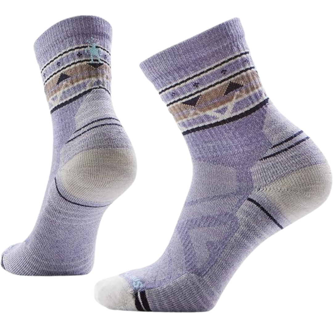 A pair of mid-calf athletic socks in a light lavender-purple color with a geometric pattern in beige, brown, and black, and a small turquoise logo on the cuff.