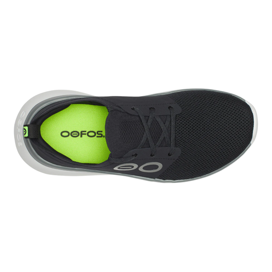 A top-down view of a black OOFOS athletic shoe with a bright neon green insole lining and a white midsole, set against a plain white background.