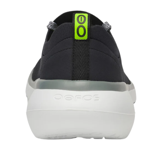 A single Oofos shoe shown from the back, featuring a black upper, a thick white sole, and a bright neon green pull tab with black 'OO' lettering.