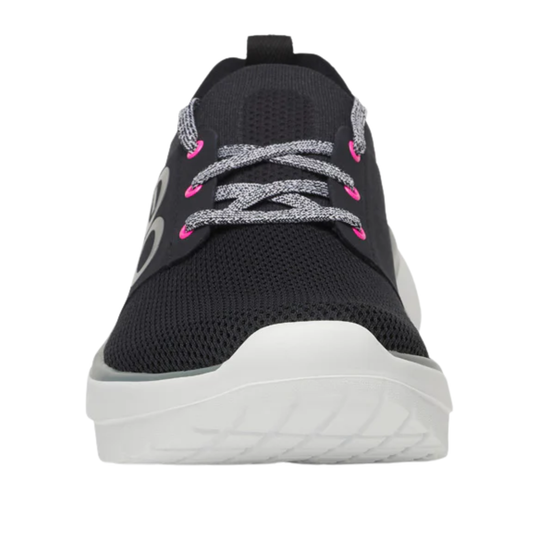 A black mesh athletic sneaker with gray and white speckled laces, bright pink eyelets, and a thick white sole, shown from a front-facing angle on a white background.