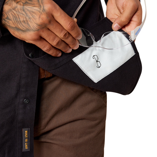 Person holding a black and white eyeglass case with a logo, wearing a black shirt.
