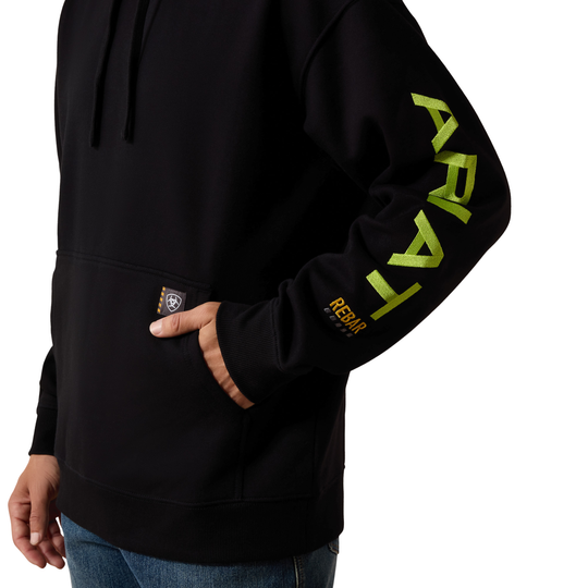 A close-up of a person wearing a black pullover hoodie with a large lime green 'ARAI' logo printed vertically on the right sleeve and a small 'REBAR' patch on the pocket, set against a plain white background.