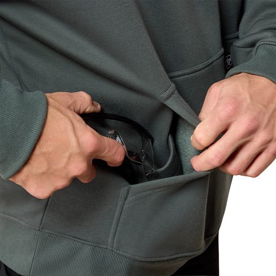 Close-up of a person wearing a dark gray hoodie and pulling a black pocket watch out of a front pocket.