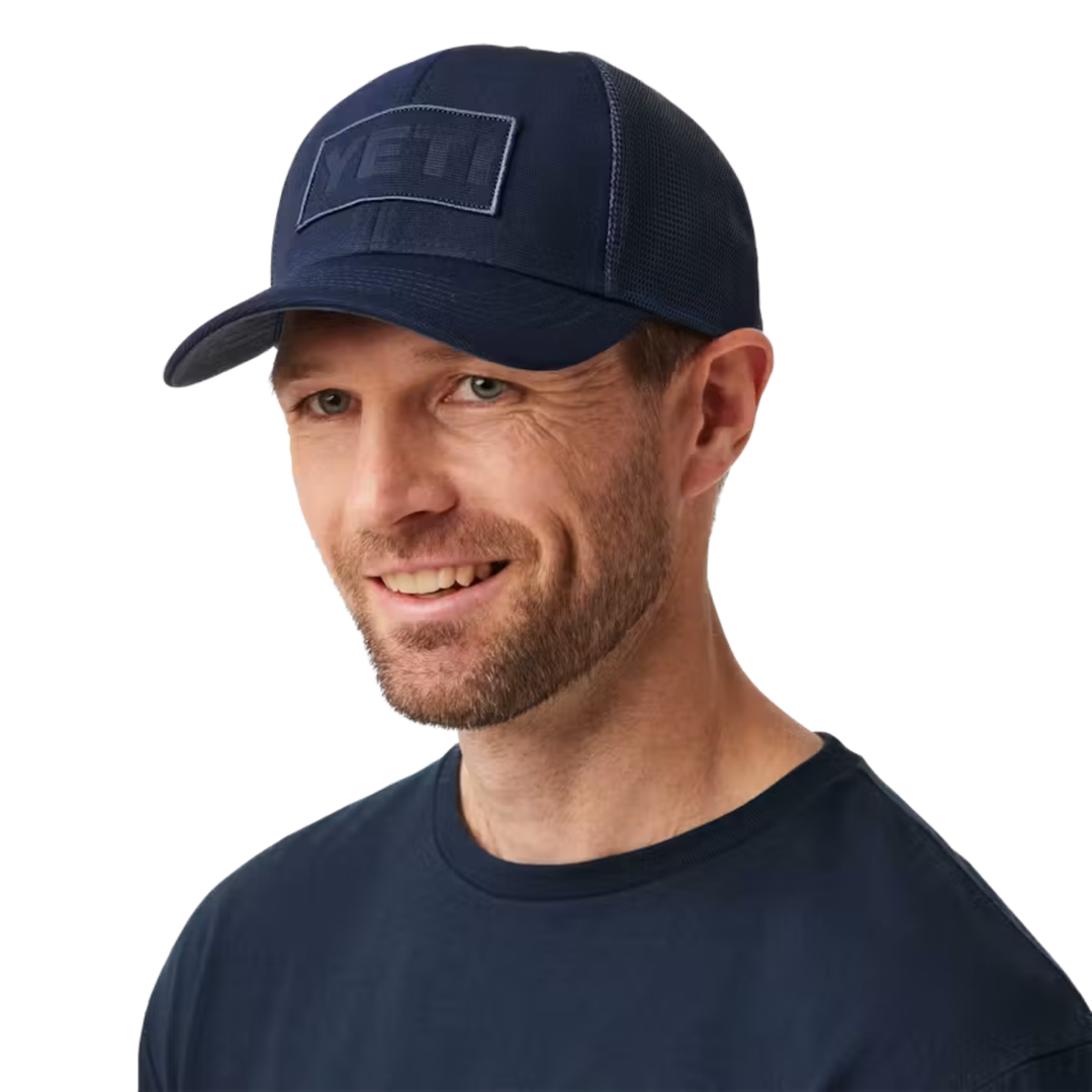 Man wearing a navy blue cap with a logo on a white background
