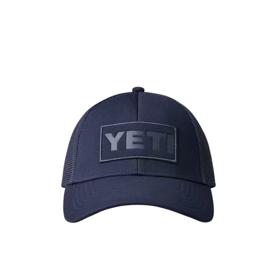 A navy blue YETI trucker hat with a dark gray embroidered YETI logo patch on the front, set against a plain white background.