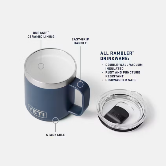A navy blue YETI Rambler insulated mug with a clear lid, shown on a light gray background with callout lines and text highlighting features like ceramic lining, easy-grip handle, stackable design, and Rambler drinkware certifications.