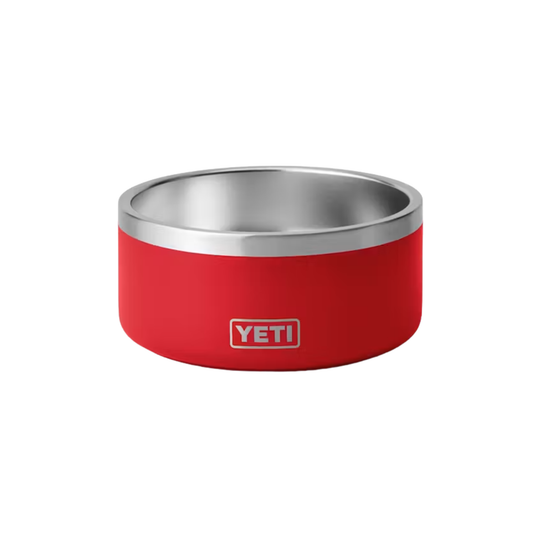 A red YETI pet bowl with a brushed stainless steel interior and rim, featuring the YETI logo on the front, set against a plain white background.