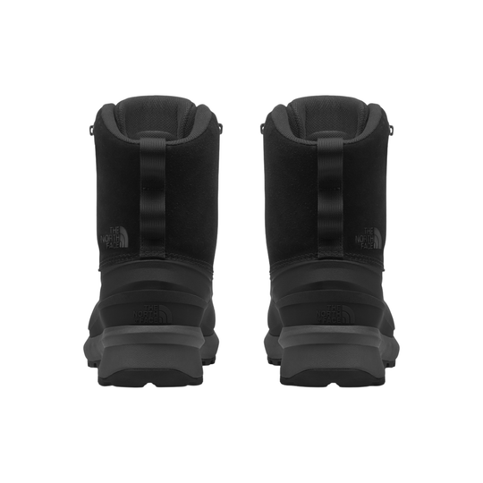 A pair of black mid-calf winter boots shown from the back, featuring a pull tab and thick rugged soles, set against a plain white background.