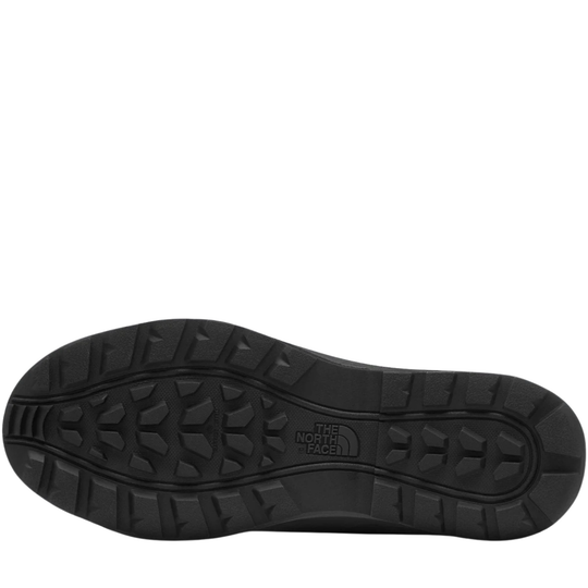 The bottom sole of a black shoe, showing deep tread patterns and the embossed logo of The North Face, on a plain white background.