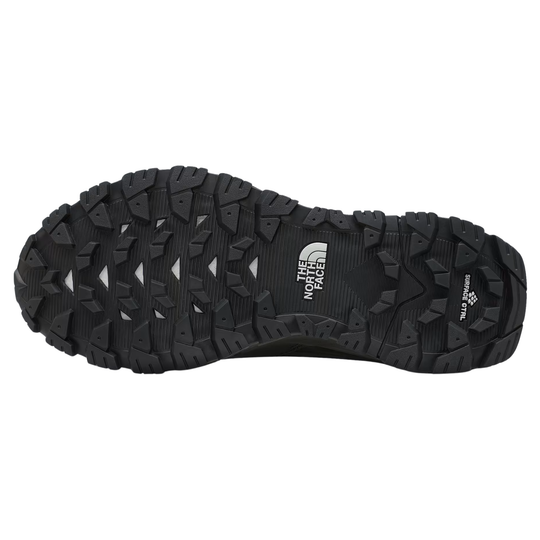 The black rubber outsole of a hiking boot by The North Face, showing deep lugs and the brand logo on the heel, isolated on a white background.