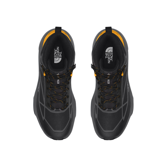 A pair of black and dark gray The North Face hiking shoes shown from a top-down view, featuring bright yellow accents on the collar, laces, and logo details.