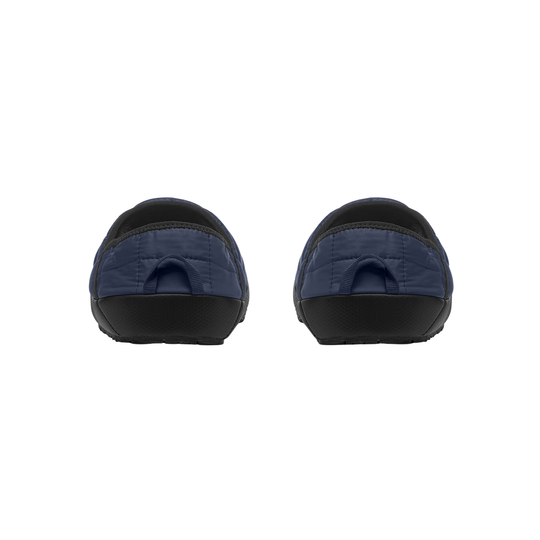 A pair of slip-on clogs shown from the back, featuring navy blue quilted uppers and black soles, set against a plain white background.