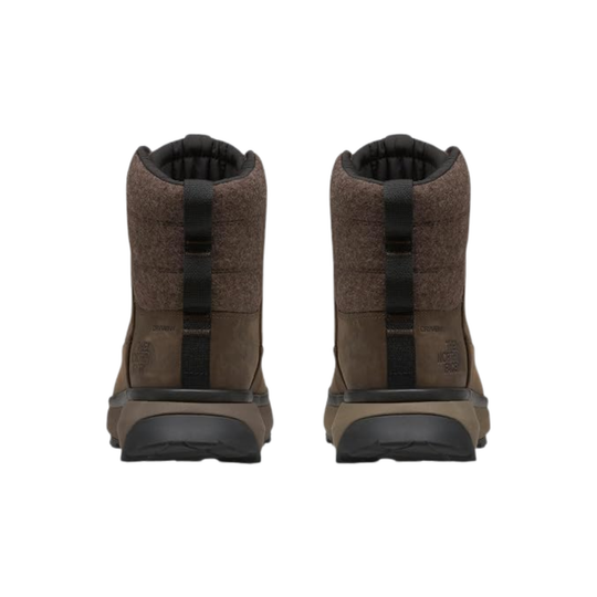 A pair of mid-height brown boots shown from the back, featuring a textured brown upper, a vertical black pull tab, and a thick black and brown sole, set against a plain white background.
