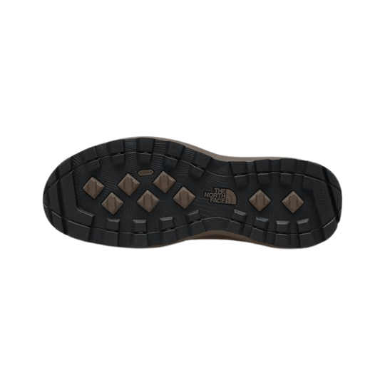 The outsole of a hiking boot by The North Face, showing a black tread pattern with brown diamond-shaped lugs and a small white brand logo in the center.