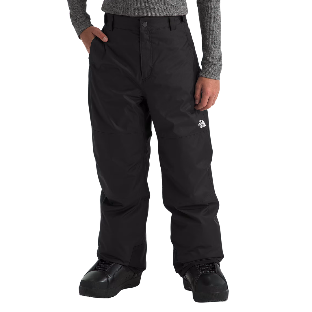 Black snowboard pants with a small white The North Face logo on the left thigh, shown on a model wearing a gray long-sleeve shirt and black snowboard boots against a white background.