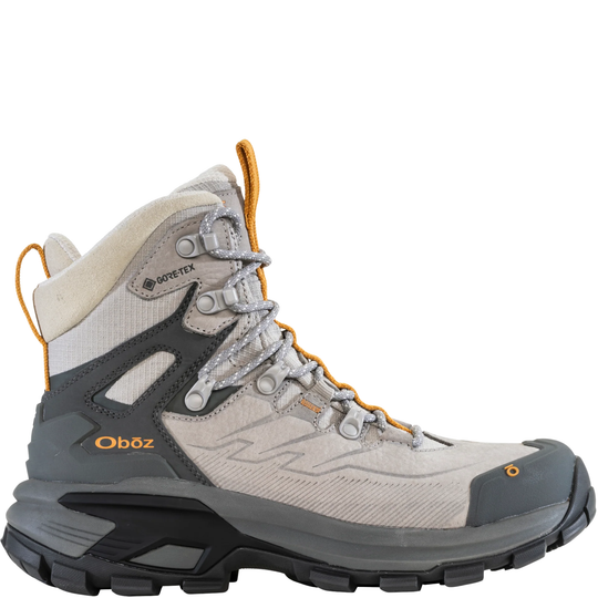 A high-top Oboz hiking boot in light gray and beige with dark gray overlays, orange accents, and a black sole, shown against a plain white background.