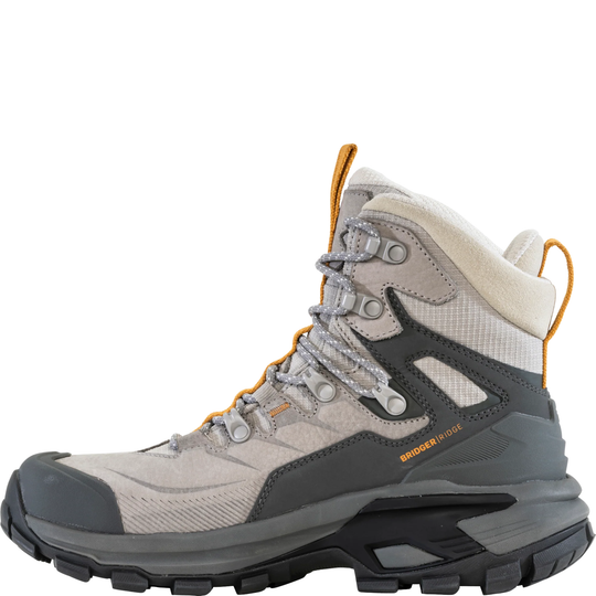 A single Brooks hiking boot in light gray and dark gray with orange accents, featuring a thick black and gray lug sole, shown against a plain white background.