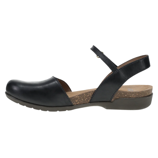 A black leather flat sandal with a low wedge heel, featuring a cork-textured midsole insert and a thin ankle strap with a small metal buckle, shown in profile against a white background.