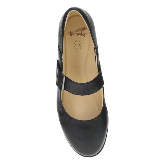 A single black leather Mary Jane shoe shown from a top-down view on a white background. The shoe features a wide strap with a silver-tone metal buckle and a tan insole with the brand name 'dansko' printed inside.
