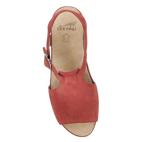 A single women's wedge sandal in dusty rose red suede, shown from a top-down view against a plain white background. The sandal features a cutout design, a side buckle strap, and a beige insole with the brand name 'dansko' printed on it.
