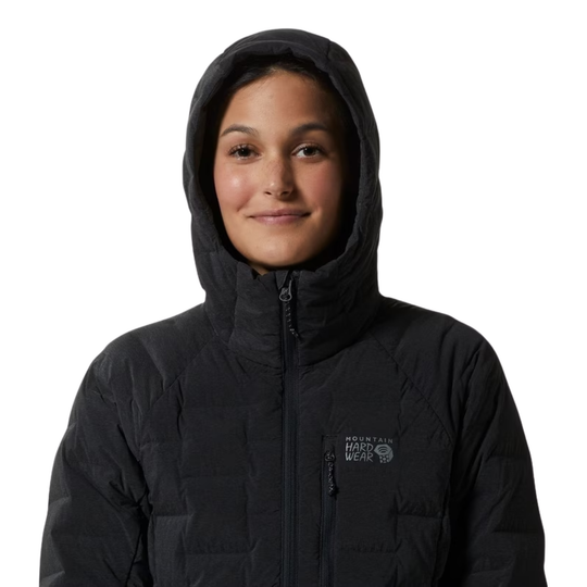A woman wearing a black hooded puffer jacket with a visible 'Mountain Hardwear' logo on the left chest, photographed against a plain white background.