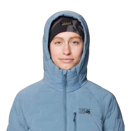 A person wearing a light blue hooded jacket with a black patterned beanie underneath, shown against a plain white background. The jacket has a visible 'Mountain Hardwear' logo on the left chest.