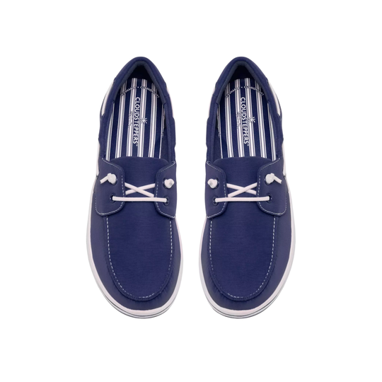 A pair of navy blue boat shoes with white laces and white stitching, shown from a top-down view on a white background. The brand name 'Sperry' is visible on the striped insole.