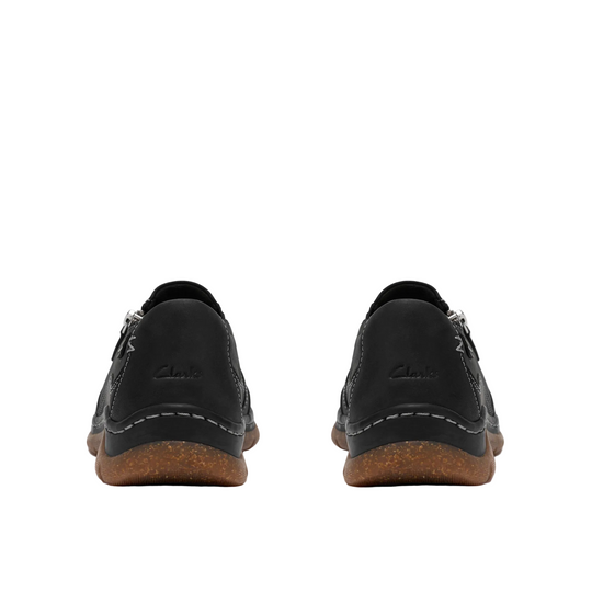A pair of black Clarks lace-up shoes shown from the back, featuring black leather uppers, white contrast stitching, and brown cork-look soles, set against a plain white background.