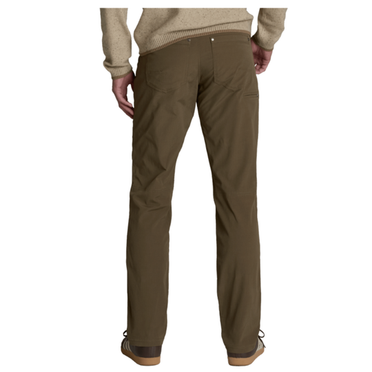 A person wearing olive brown pants, a beige sweater, and brown sneakers with white stripes, shown from the waist down against a plain white background.