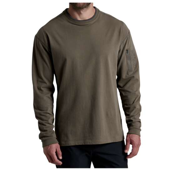 A man wearing an olive green long-sleeve crewneck shirt with a vertical zippered pocket on the left sleeve, shown against a plain white background.
