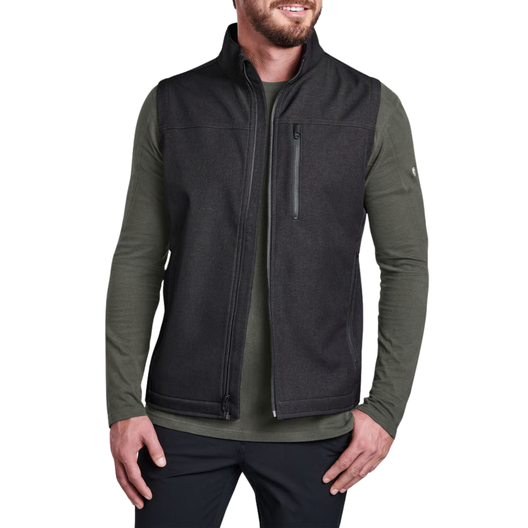 A man wearing a dark charcoal zip-up fleece vest over an olive green long-sleeve shirt, shown from the waist up against a plain white background.